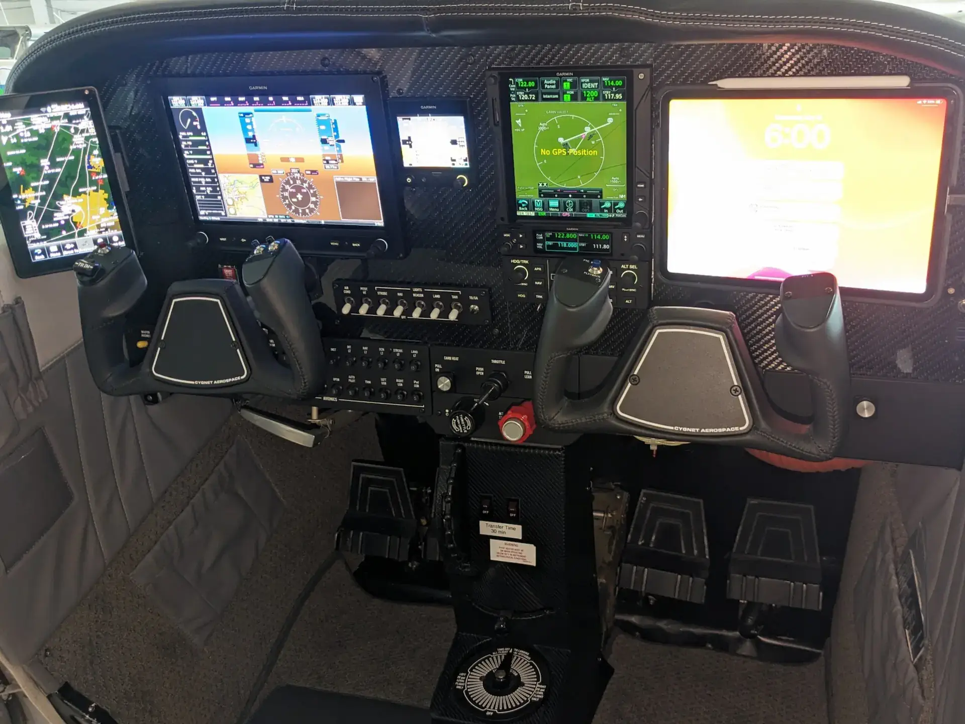 Cockpit view of a modern aircraft featuring multiple digital flight displays, control yokes, foot pedals, and navigation instruments.